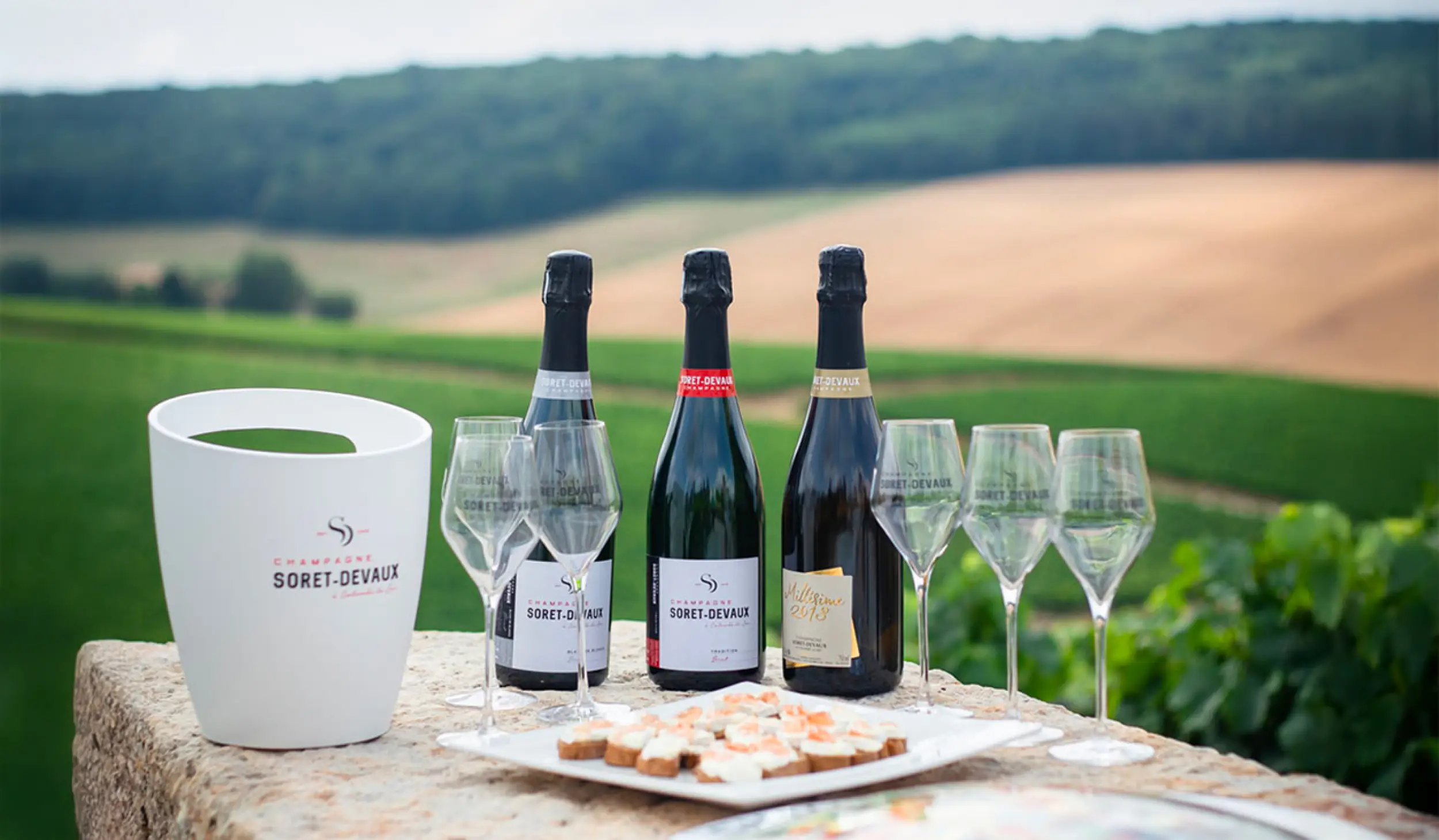 Bouteilles et flutes de champagnes Soret-Devaux sur une table en pierre lors d'une dégustation
